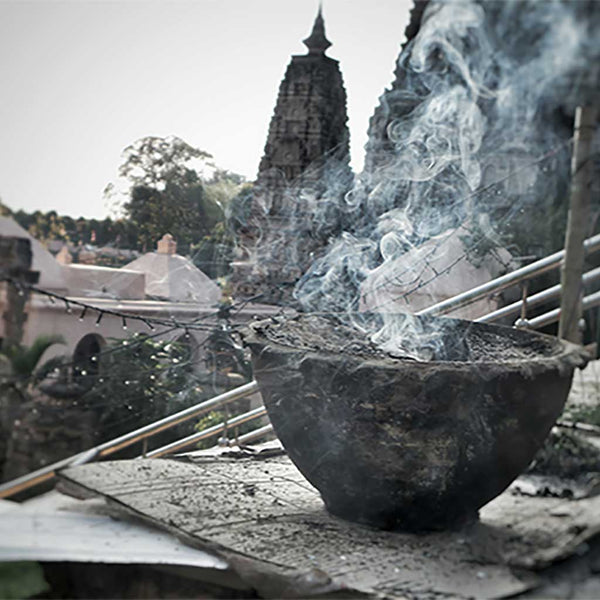 Encens brûlant dans un bol devant un stupa bouddhiste, fumée s'élevant, ambiance méditative