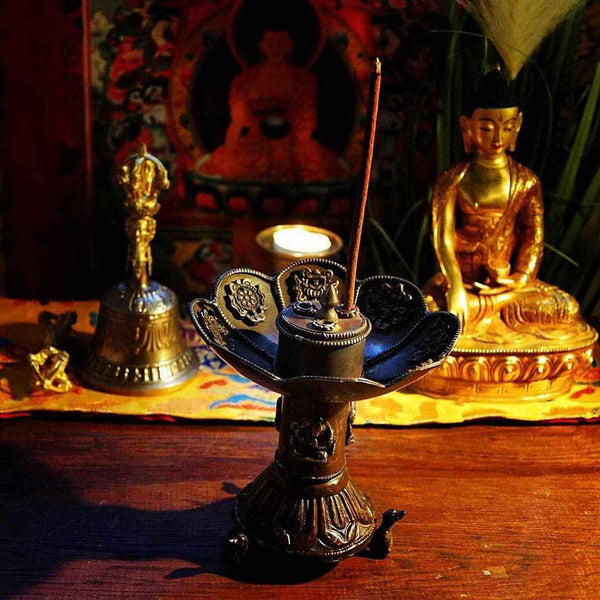 Brûle-encens bouddhiste tibétain avec statue de Bouddha et cloche rituelle sur autel