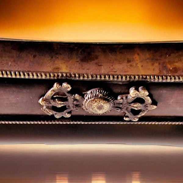 Détail ornemental bouddhiste tibétain avec symboles sacrés et finitions métalliques