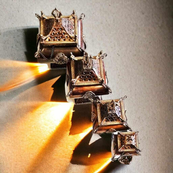 Brûle-encens tibétain en métal doré, orné de motifs traditionnels bouddhistes, éclairé par la flamme