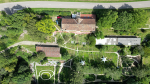 Vue aérienne d'un centre bouddhiste avec jardins, drapeaux de prière et bâtiments entourés de verdure