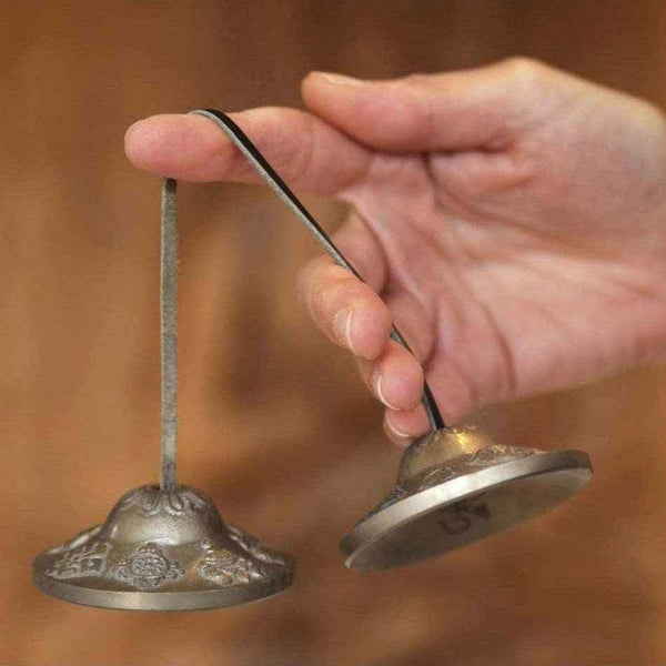 Cloches tibétaines en métal pour méditation bouddhiste, tenues par une main