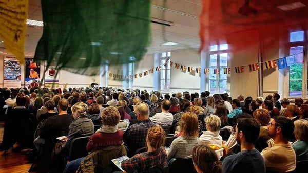 Auditoire lors d'une conférence sur la méditation bouddhiste avec drapeaux tibétains