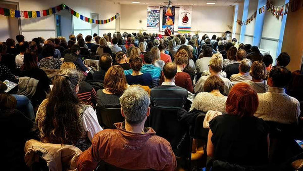 Conférence sur la méditation bouddhiste avec public attentif, drapeaux tibétains et enseignement spirituel