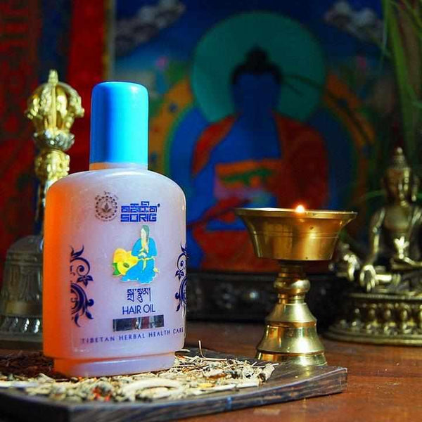 Huile capillaire tibétaine à base de plantes, avec bouddha et lampe à huile en arrière-plan