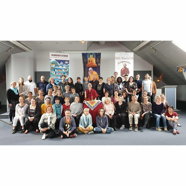 Groupe lors d'une conférence sur la méditation bouddhiste avec enseignant en robe rouge, bannières sur le calme mental et la compassion