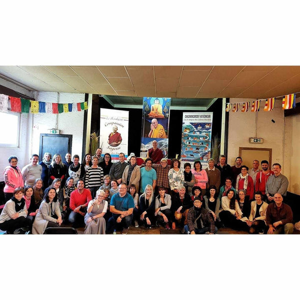 Groupe lors d'une conférence sur la méditation bouddhiste avec drapeaux tibétains et livres de philosophie