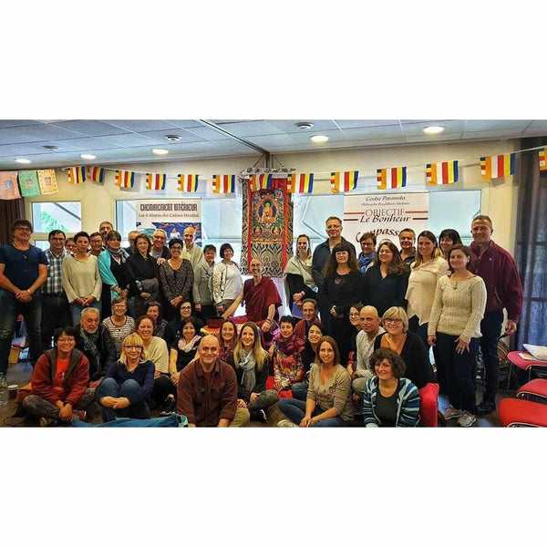 Groupe lors d'une conférence sur la méditation bouddhiste tibétaine avec drapeaux et thangka