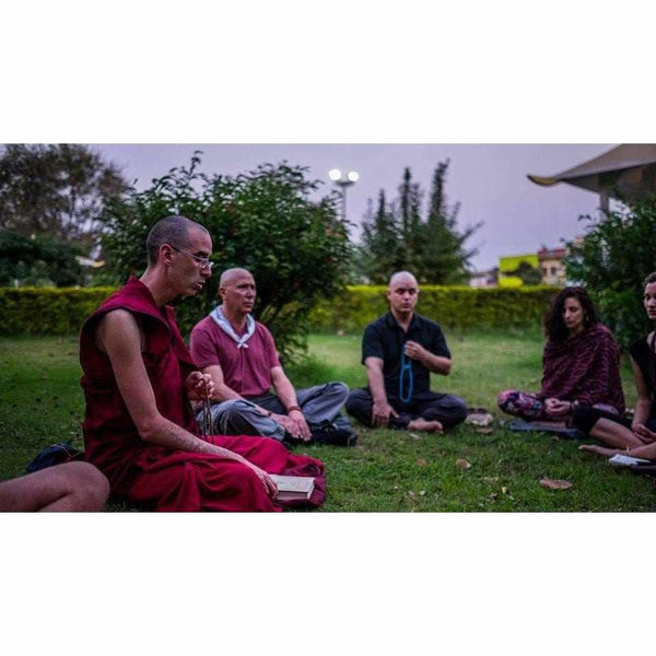 Lama en robe rouge enseignant la méditation en plein air à un groupe, philosophie bouddhiste tibétaine