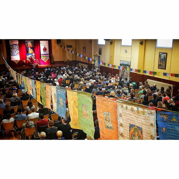 Conférence de méditation bouddhiste avec drapeaux tibétains et public attentif