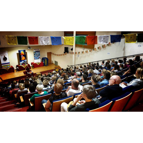 Conférence sur la méditation bouddhiste avec drapeaux tibétains et public attentif