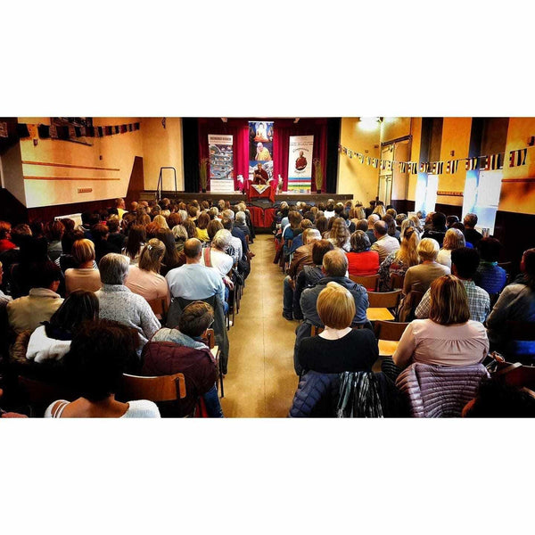 Auditoire lors d'une conférence sur la méditation et la philosophie bouddhiste tibétaine, avec drapeaux traditionnels.