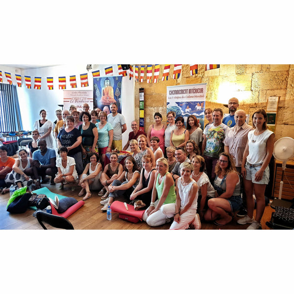 Groupe souriant lors d'une session de méditation bouddhiste tibétaine avec drapeaux et bannières sur le calme mental