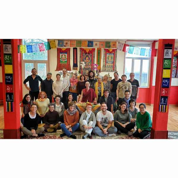 Groupe souriant lors d'une session de méditation bouddhiste avec drapeaux tibétains et thangkas