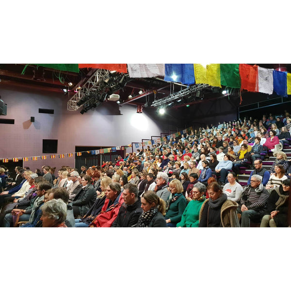 Auditoire lors d'une conférence sur la méditation bouddhiste avec drapeaux tibétains