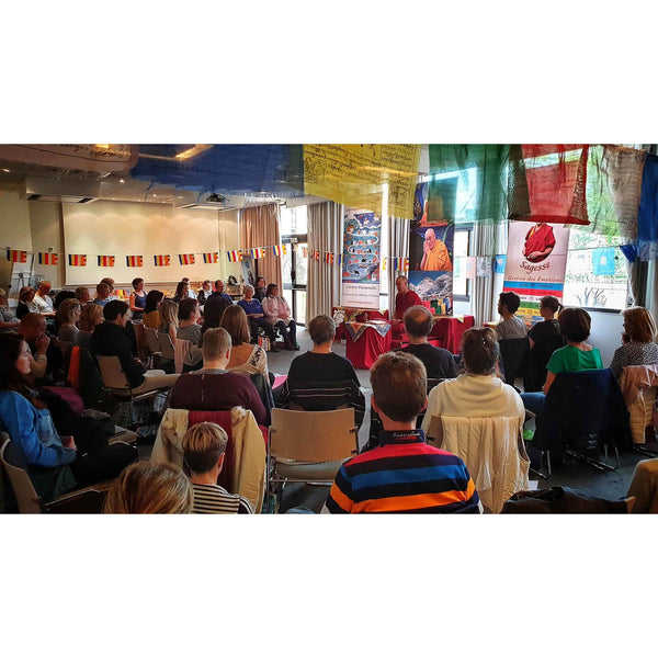 Conférence sur la philosophie bouddhiste tibétaine avec drapeaux et enseignement du Lama Samten