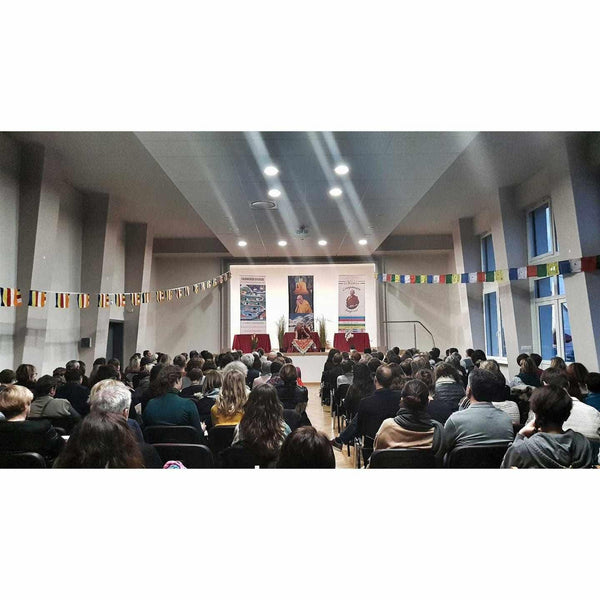 Conférence sur la méditation bouddhiste avec drapeaux tibétains et public attentif