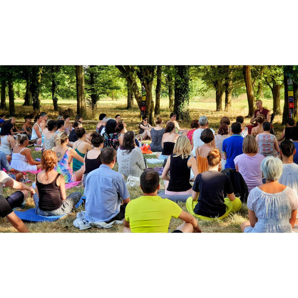 Groupe en méditation bouddhiste en plein air, enseignement sous les arbres avec drapeaux tibétains