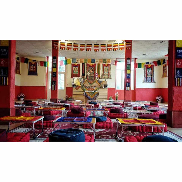 Salle de méditation bouddhiste tibétaine avec drapeaux, coussins et autels pour pratiques spirituelles
