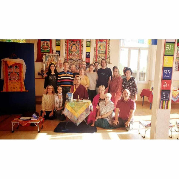 Groupe lors d'une conférence sur la méditation bouddhiste avec thangkas et objets tibétains