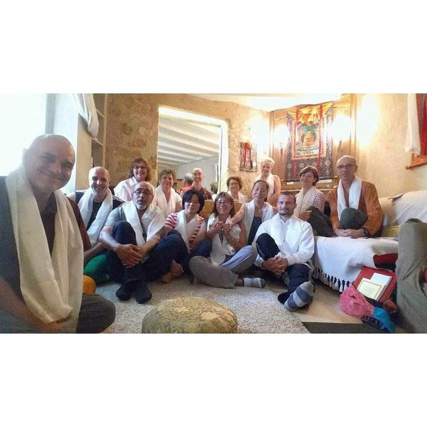 Groupe en méditation bouddhiste avec écharpes blanches, dans un centre de pratique tibétaine