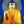 Statue de Bouddha dorée avec robe orange et halo scintillant, symbole de la philosophie bouddhiste tibétaine