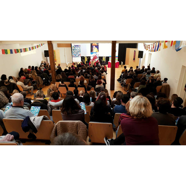 Conférence sur la méditation bouddhiste avec public attentif et drapeaux tibétains