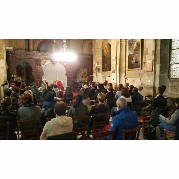Conférence sur la méditation bouddhiste avec un maître en robe rouge devant un public attentif