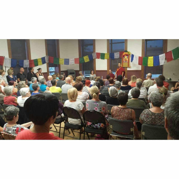 Conférence sur la méditation bouddhiste avec drapeaux tibétains et public attentif