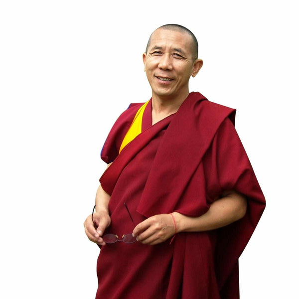 Lama bouddhiste tibétain en robe rouge, souriant, tenant ses lunettes, enseignant la méditation et la philosophie bouddhiste.