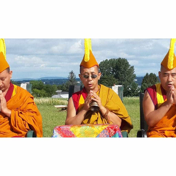 Moines bouddhistes tibétains en méditation avec cloche rituelle en extérieur