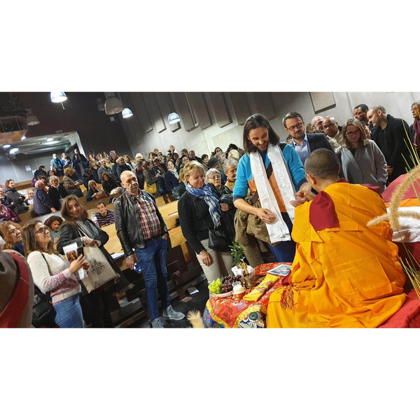 Lama en robe orange reçoit un khata blanc lors d'une conférence sur la méditation bouddhiste tibétaine