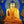 Statue de Bouddha dorée avec robe orange, halo scintillant, sur fond bleu, objets tibétains