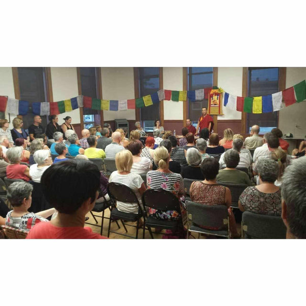 Conférence de méditation bouddhiste avec drapeaux tibétains et public attentif