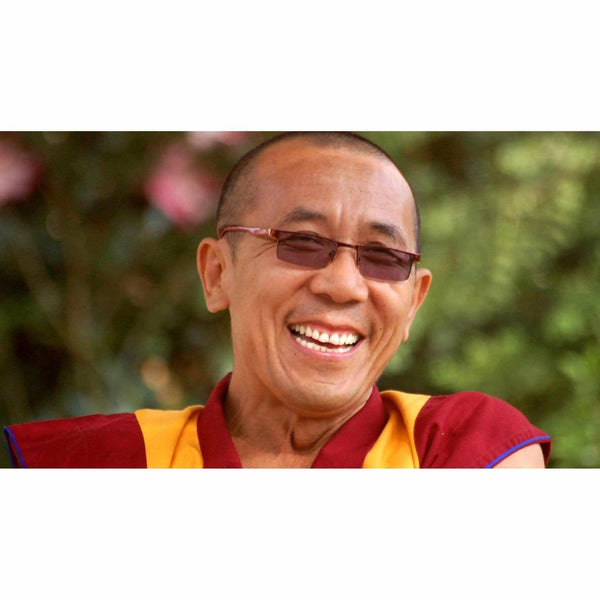 Moine bouddhiste tibétain souriant en robe traditionnelle, lunettes, fond verdure