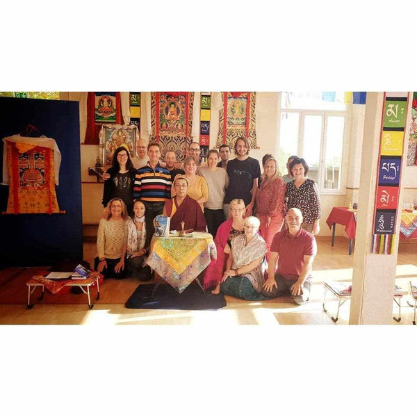 Groupe en méditation bouddhiste tibétaine avec maître Lama Samten, thangkas et drapeaux prières