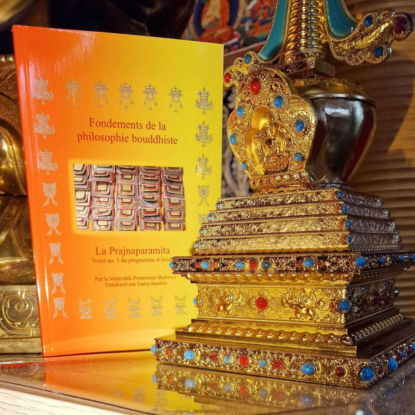 Livre 'Fondements de la philosophie bouddhiste' et stupa tibétain orné de pierres précieuses