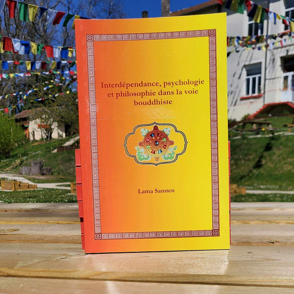 Livre de philosophie bouddhiste par Lama Samten sur l'interdépendance et la psychologie, avec drapeaux tibétains en arrière-plan