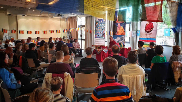 Conférence sur la philosophie bouddhiste tibétaine avec Lama Samten, drapeaux prières, public attentif
