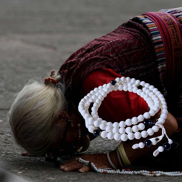Femme tibétaine en prière avec mala blanc, symbole de méditation bouddhiste et spiritualité himalayenne
