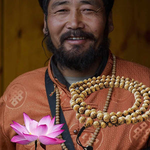 Lama bouddhiste souriant avec mala tibétain et fleur de lotus, symboles de méditation et sagesse bouddhique