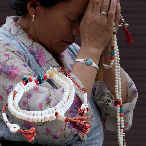 Méditation bouddhiste avec mala en perles blanches et tibétaines, symbole de paix et spiritualité