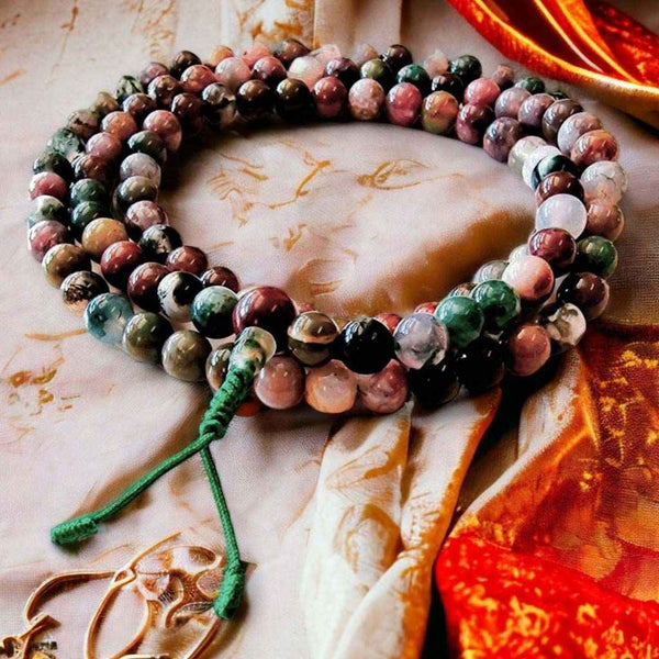 Chapelet bouddhiste en pierres naturelles multicolores pour méditation, posé sur tissu traditionnel