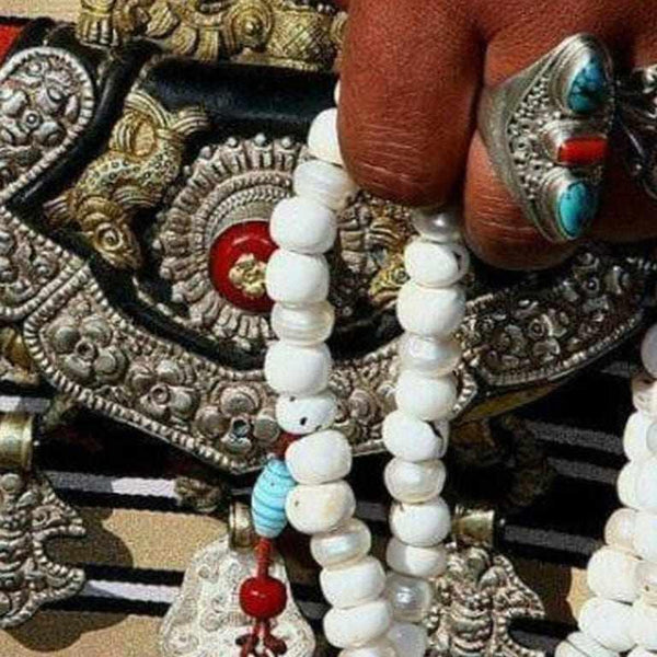 Perles de prière bouddhistes blanches avec bijoux tibétains et anneau turquoise, symboles de méditation et spiritualité