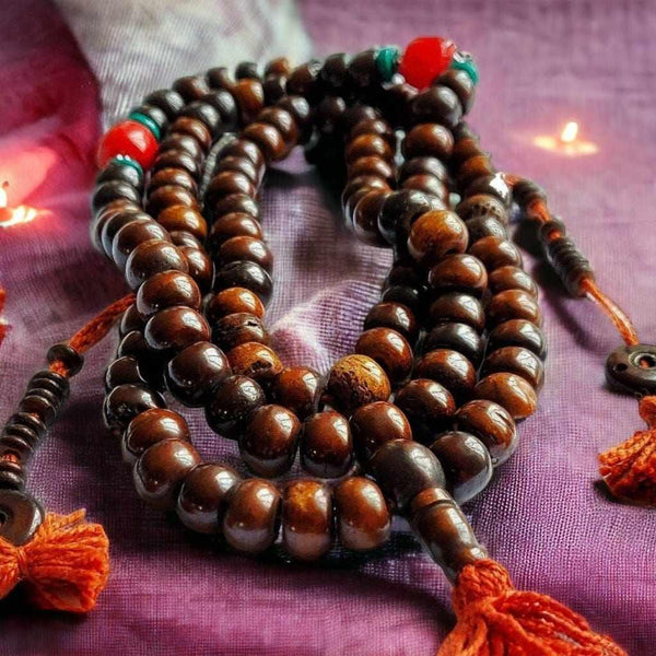 Mala bouddhiste en bois avec perles rouges et tresses orange, symbole de méditation et philosophie tibétaine