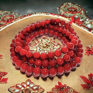 Chapelet bouddhiste en perles rouges sur tissu décoratif tibétain, symbole de méditation et spiritualité