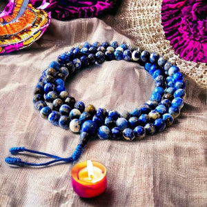 Mala bouddhiste en pierres bleues avec bougie, objets de méditation et culture tibétaine