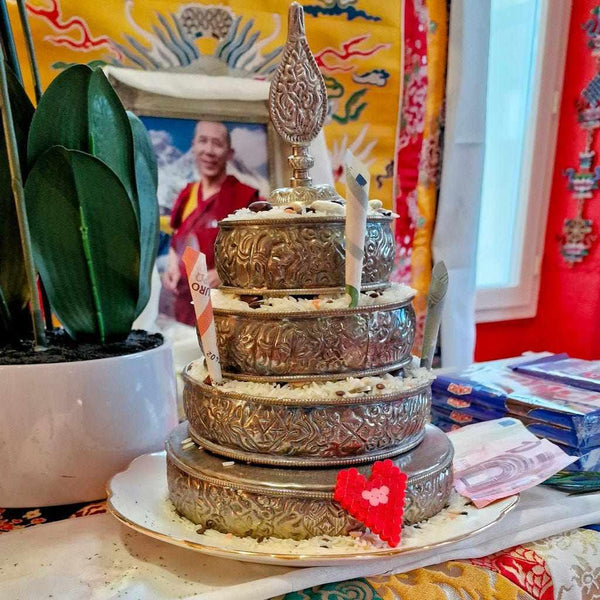 Offrande bouddhiste tibétaine en métal ciselé avec riz et billets, devant photo de Lama Samten