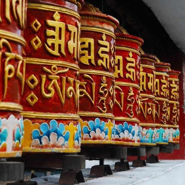 Roues de prière tibétaines rouges ornées de mantras dorés et motifs colorés