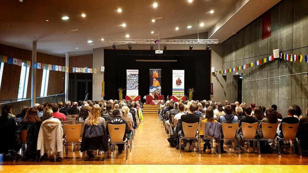 Conférence sur la méditation bouddhiste avec drapeaux tibétains et public attentif
